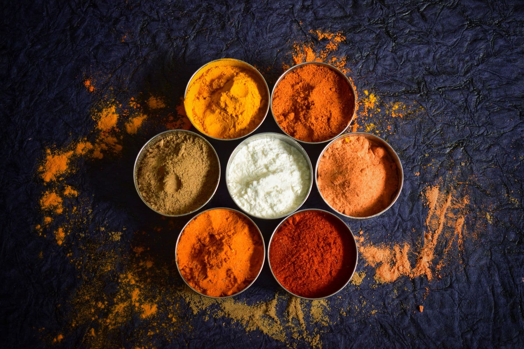 An assortment of colourful ground spices in bowls